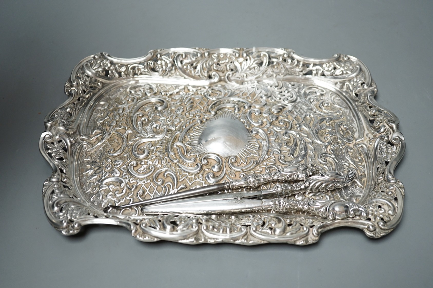 A late Victorian repousse silver dressing table tray, Birmingham, 1898, 30.5cm, together with tow silver mounted brushes, mounted button hook and glove stretchers.